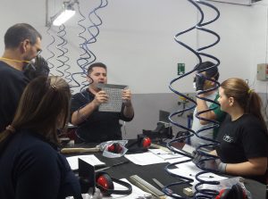 Profesor enseñando a medir una placa de metal durante las clases prácticas del curso Montador de Estructuras Aeronáuticas