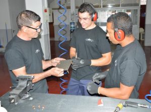 Grupo de alumnos revisando y comparando las placas de metal que han tenido que taladrar en el curso Montador Aeronáutico
