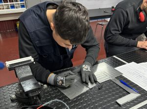 Alumno del curso Montador de Estructuras Aeronáuticas midiendo donde debe taladrar la placa de metal