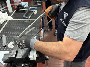 Alumno del curso Montador de Estructuras Aeronáuticas cortando piezas de metal con una sierra manual