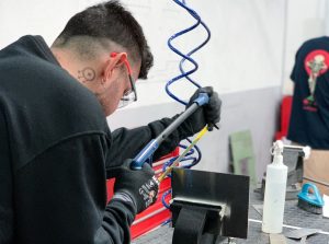 Alumno del curso Montador de Estructuras Aeronáuticas cortando con una sierra una placa de metal