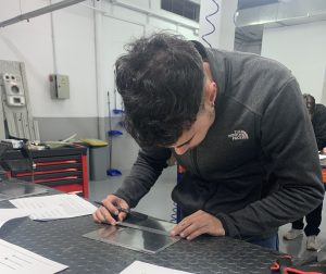 Alumno del curso Montador Aeronáutico midiendo la placa para marcar en que puntos debe taladrar
