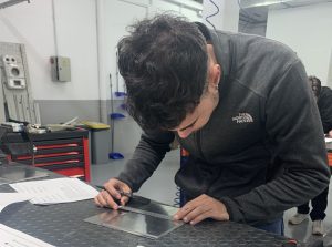 Alumno del curso Montador Aeronáutico midiendo la placa para marcar en que puntos debe taladrar