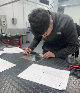 Alumno del curso Montador Aeronáutico midiendo la placa para marcar en que puntos debe taladrar