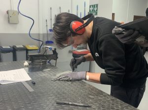 Alumno del curso Montador de Estructuras Aeronáuticas marcando una placa de metal