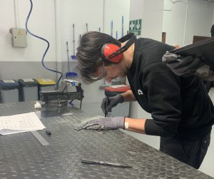 Alumno del curso Montador de Estructuras Aeronáuticas marcando una placa de metal