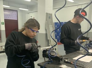 Alumna del curso Montador Aeronáutico recortando una placa de metal para su proyecto final