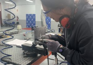 Alumna del curso Montador de Estructuras Aeronáuticas taladrando una placa de metal