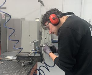 Alumno del curso Montador Aeronáutico taladrando una placa de metal para su proyecto final