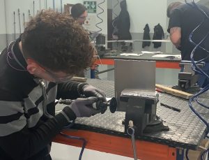 Alumno del curso Montador de Estructuras Aeronáuticas recortando una placa de metal