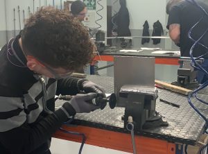 Alumno del curso Montador de Estructuras Aeronáuticas recortando una placa de metal
