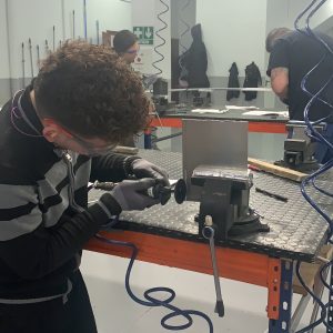 Alumno del curso Montador de Estructuras Aeronáuticas recortando una placa de metal