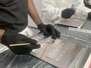 Alumno del curso Sellador Aeronáutico aplicando promotor de adhesión durante las clases prácticas del curso