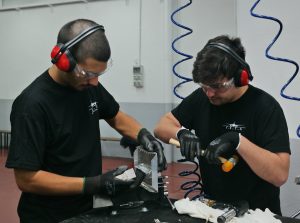 Alumnos trabajando en equipo en una placa de metal